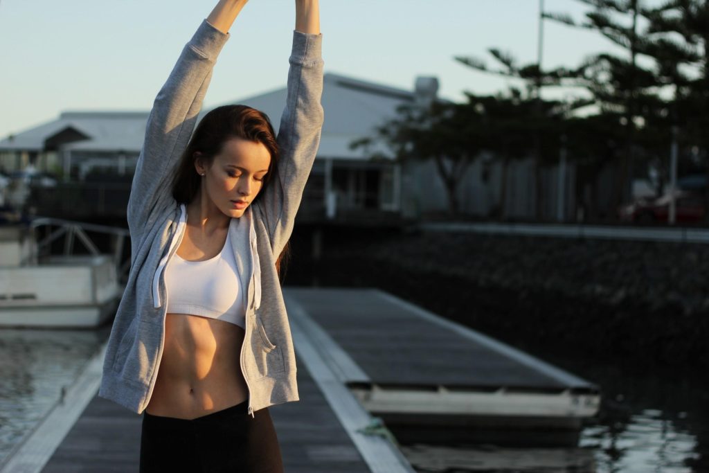 Brunette Woman Stretching Wearing White Tank Top And Grey Jacket