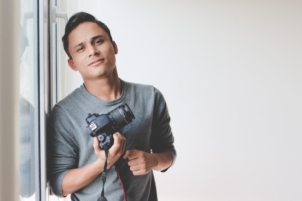 Man Holding Camera Leaning On Wall