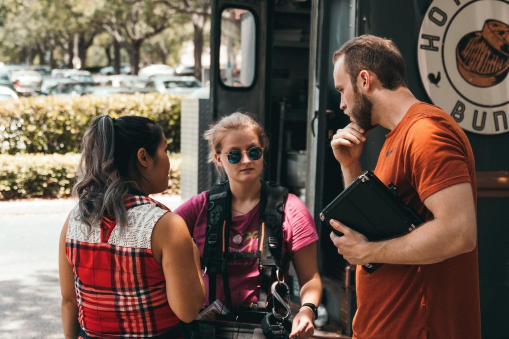 Three People Discussing In A Front Of A Van