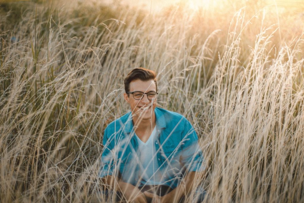 White Guy With Glasses Sitting Down In Wheat Field