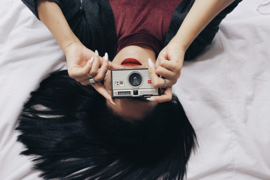 Woman Holding Up Instamatic Camera